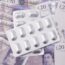 Packets of tablets resting on twenty pound notes, representing the cost to employers of the 2026 statutory sick pay changes