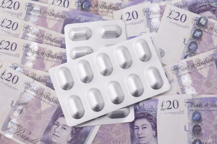 Packets of tablets resting on twenty pound notes, representing the cost to employers of the 2026 statutory sick pay changes
